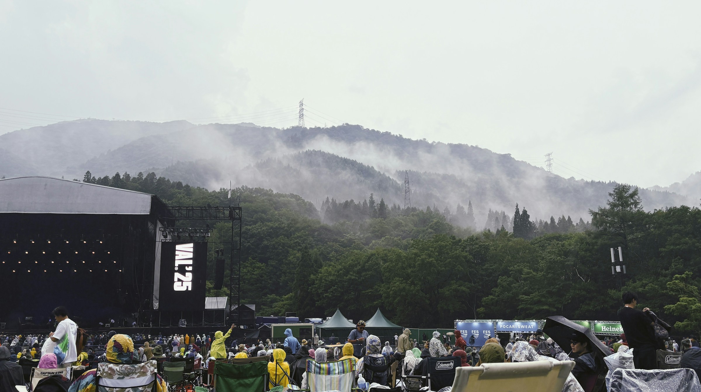Outdoor concert audience gathered beneath a misty mountain backdrop